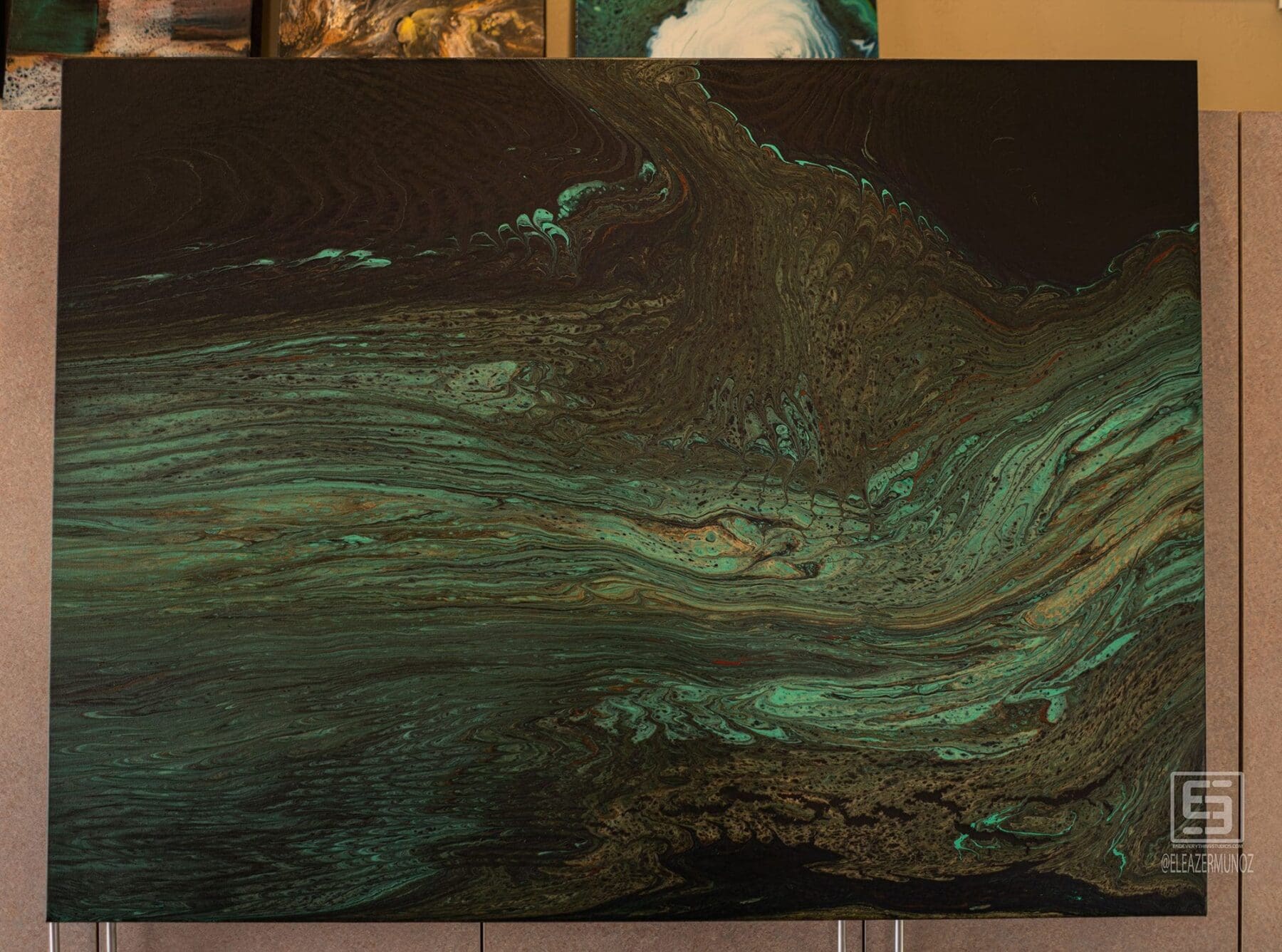 A horizontal artwork uses deep green, teal, and black flowing bands that resemble a layered wave.