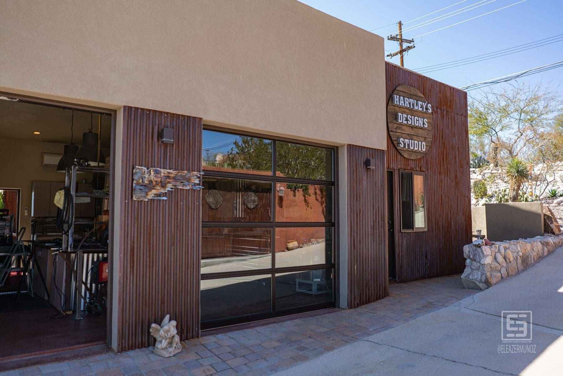 A wide exterior view shows the open studio entrance, large window, corrugated facade, and Hartley Studios sign.