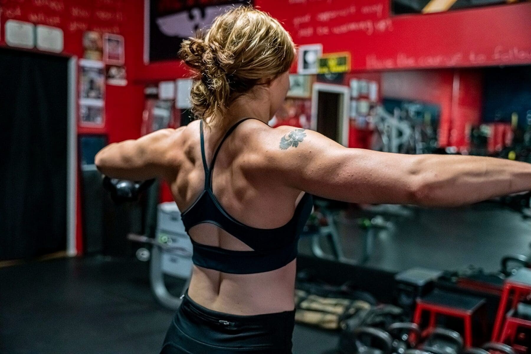 Day extends both arms in a rear pose that highlights her back and shoulders.