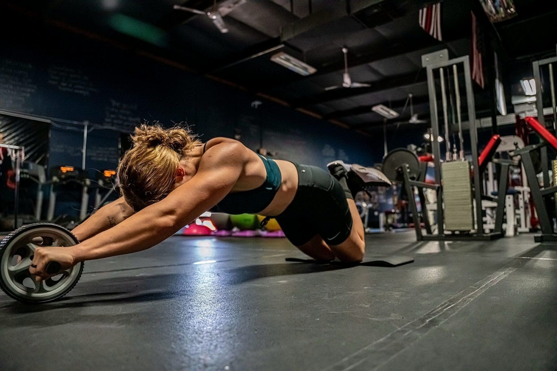 Day holds a long kneeling rollout with both hands on an ab wheel.
