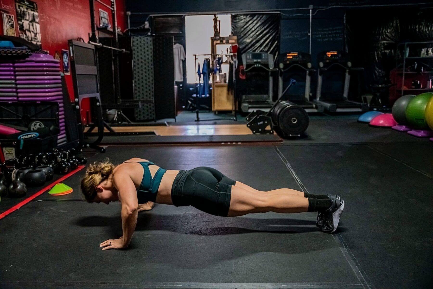A wide side view captures Day holding a straight full-body push-up position.