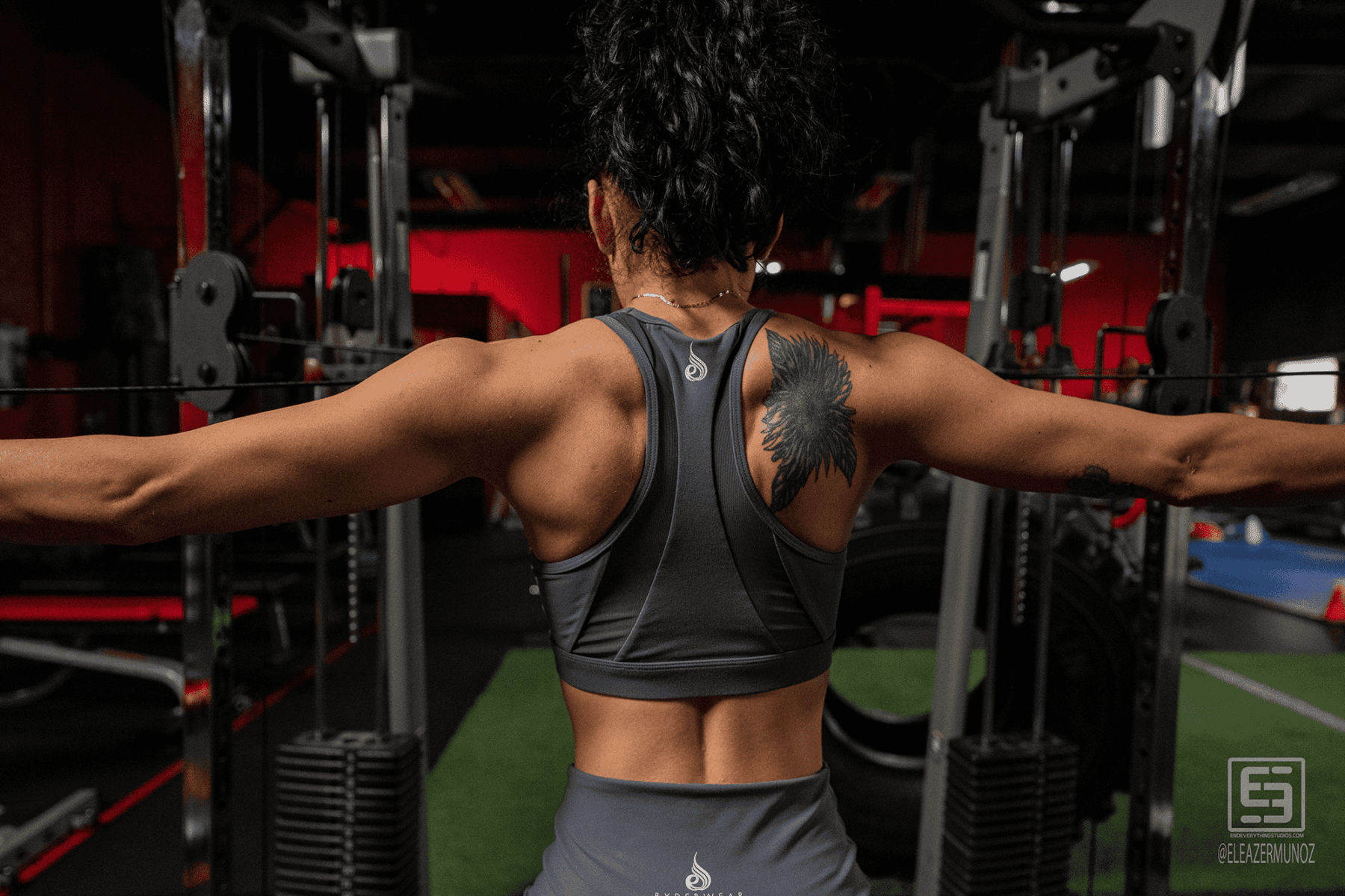 A rear gym portrait shows Cynthia extending both arms during a cable exercise.