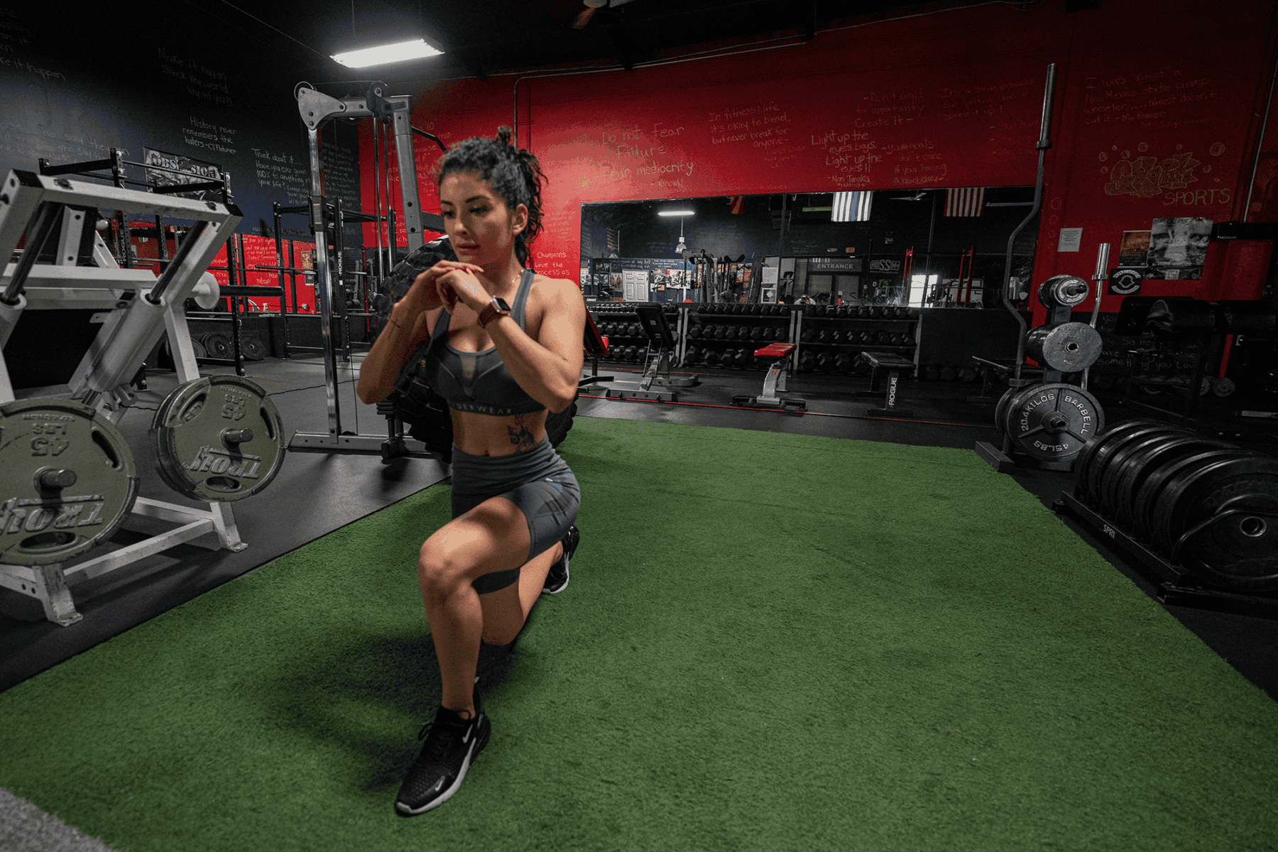 Cynthia holds a weight at her chest while stepping into a lunge.
