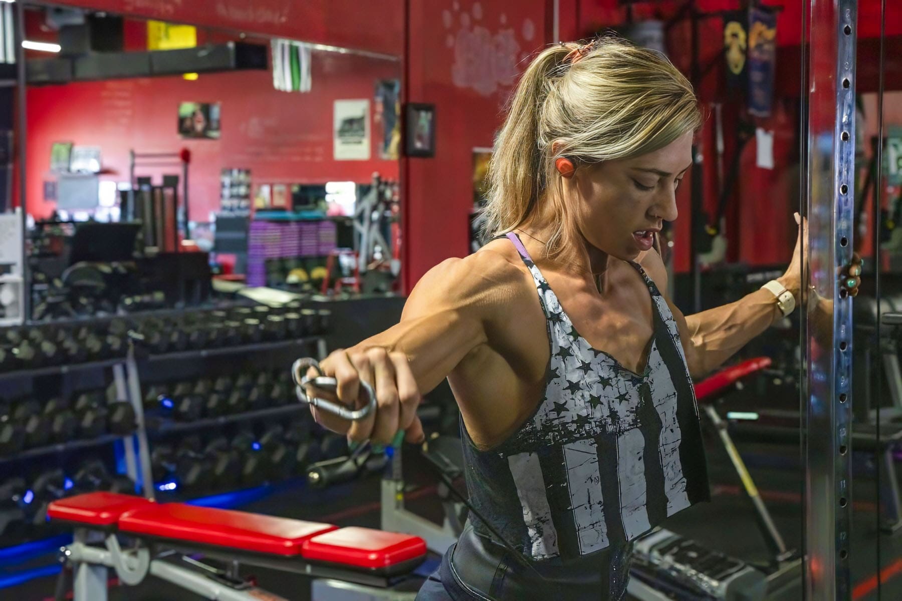L. Butler holds the cable handles open in a strong front-facing fitness portrait during a fitness portrait session in a gym.