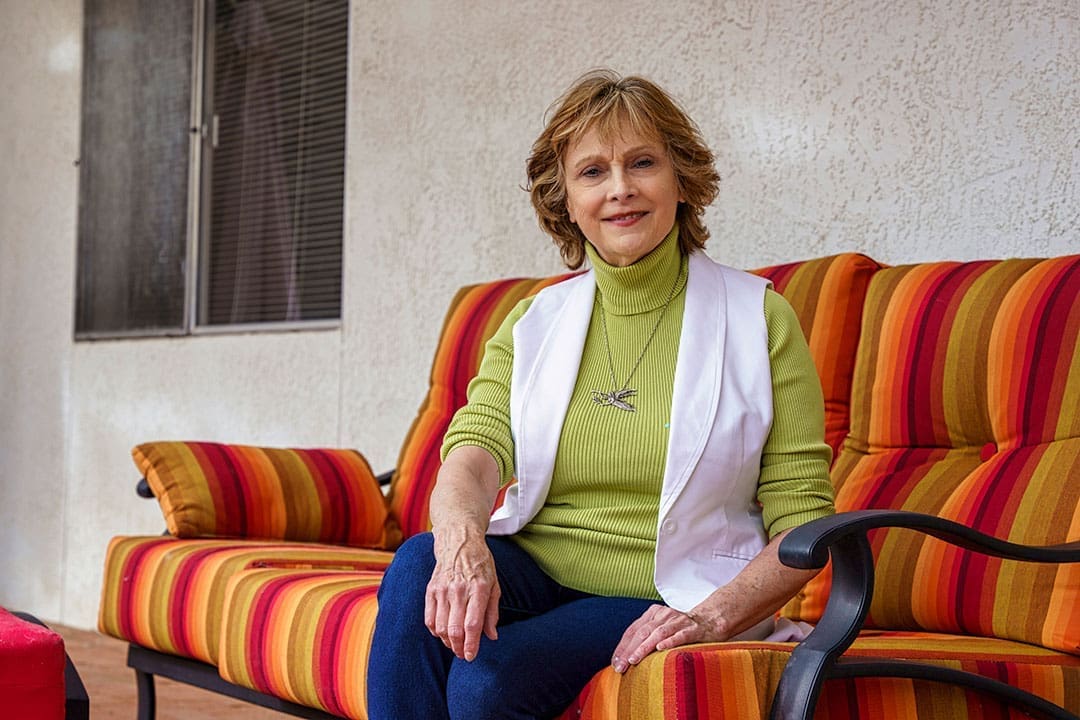 A relaxed seated portrait of Kate in a colorful interior setting.